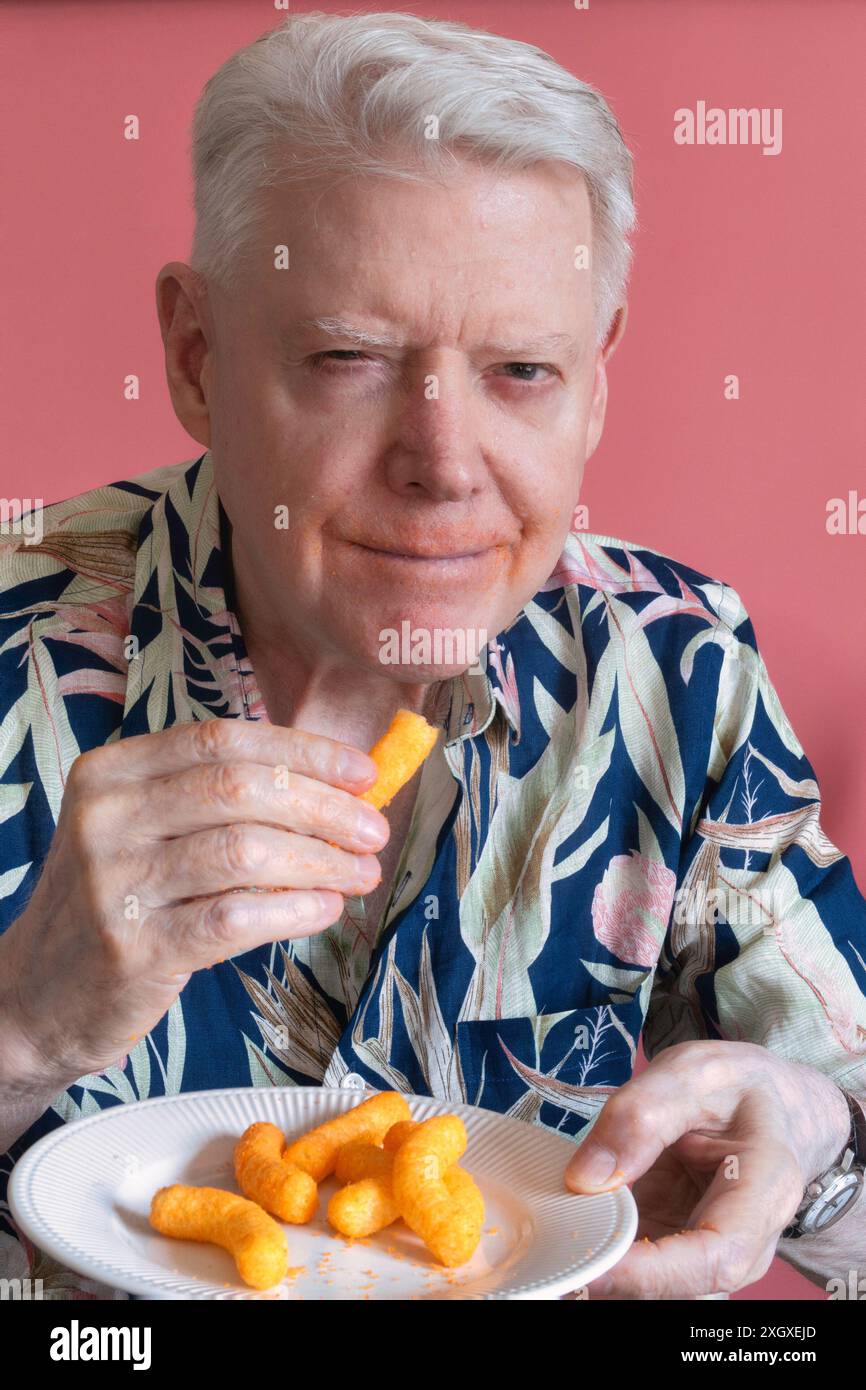 Senior-Mann, der Cheetos knabbert und ein Chaos macht, 2024, USA Stockfoto