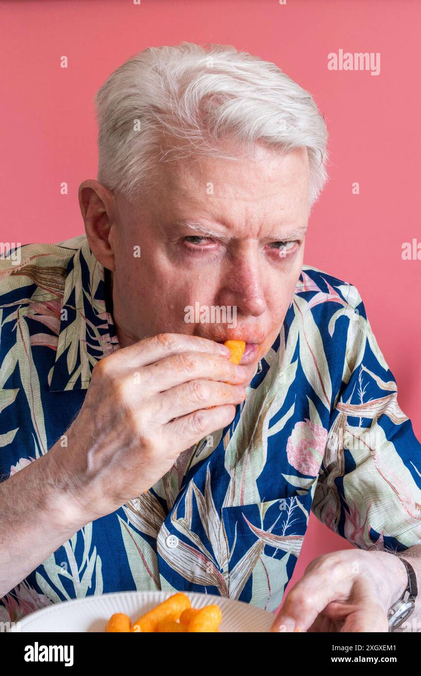 Senior-Mann, der Cheetos knabbert und ein Chaos macht, 2024, USA Stockfoto