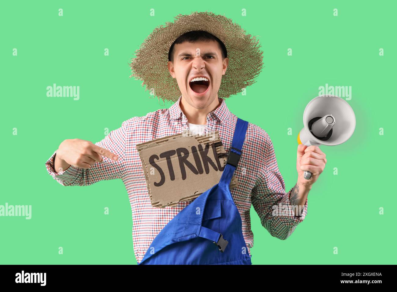 Protestierender männlicher Bauer mit Megaphon, der auf ein Plakat mit WORTSCHLAG auf grünem Hintergrund zeigt Stockfoto