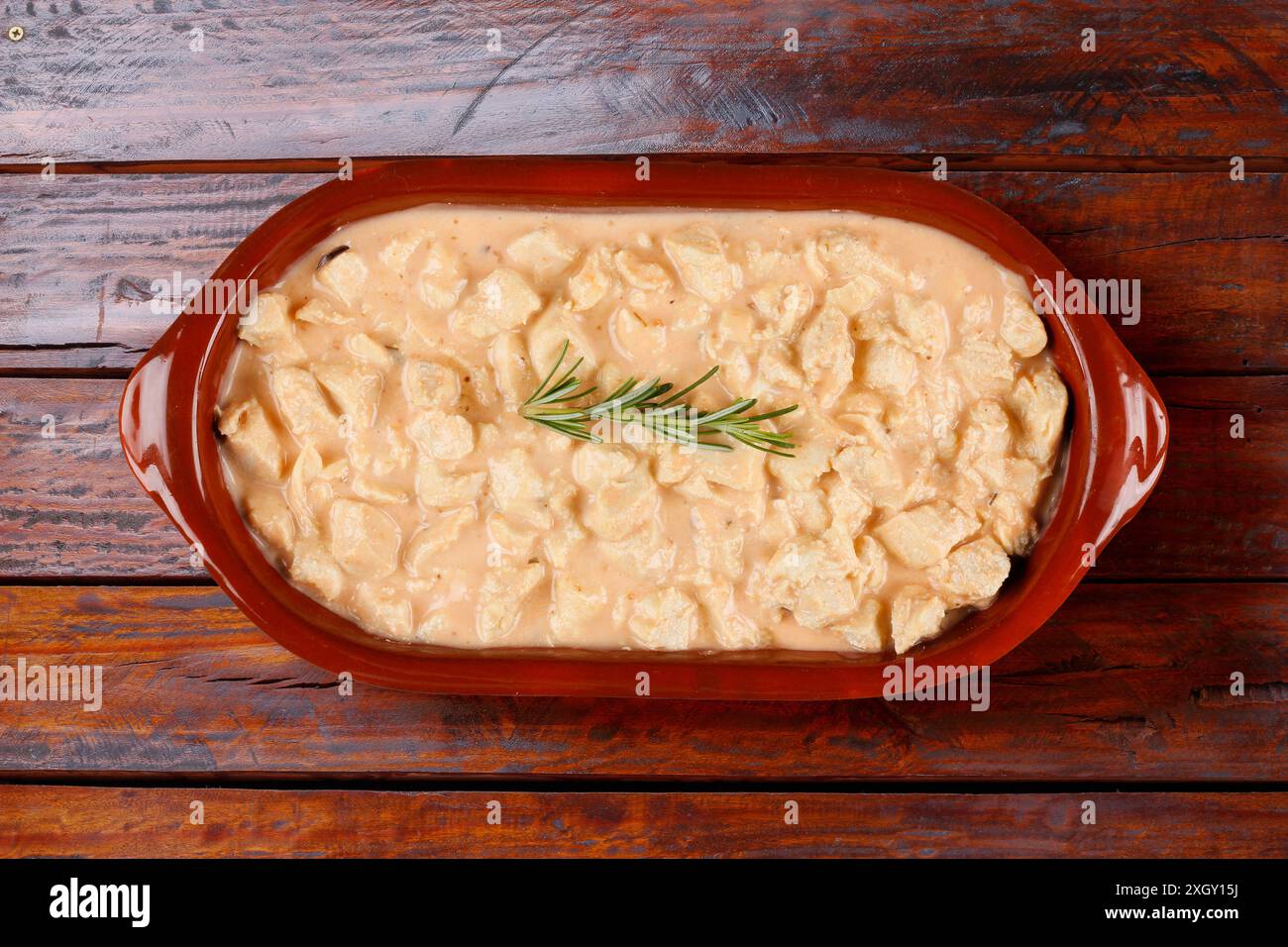 Hausgemachtes Hühnerstroganoff in Keramikschale auf rustikalem Holztisch. Draufsicht Stockfoto