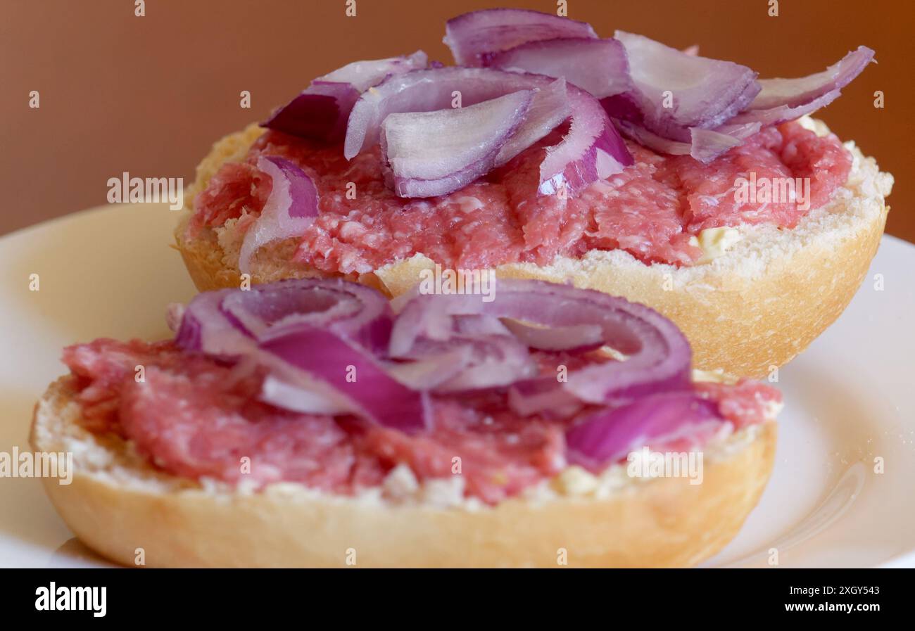 Zwei Halbmettbrötchen mit Zwiebeln auf einem Teller Stockfoto