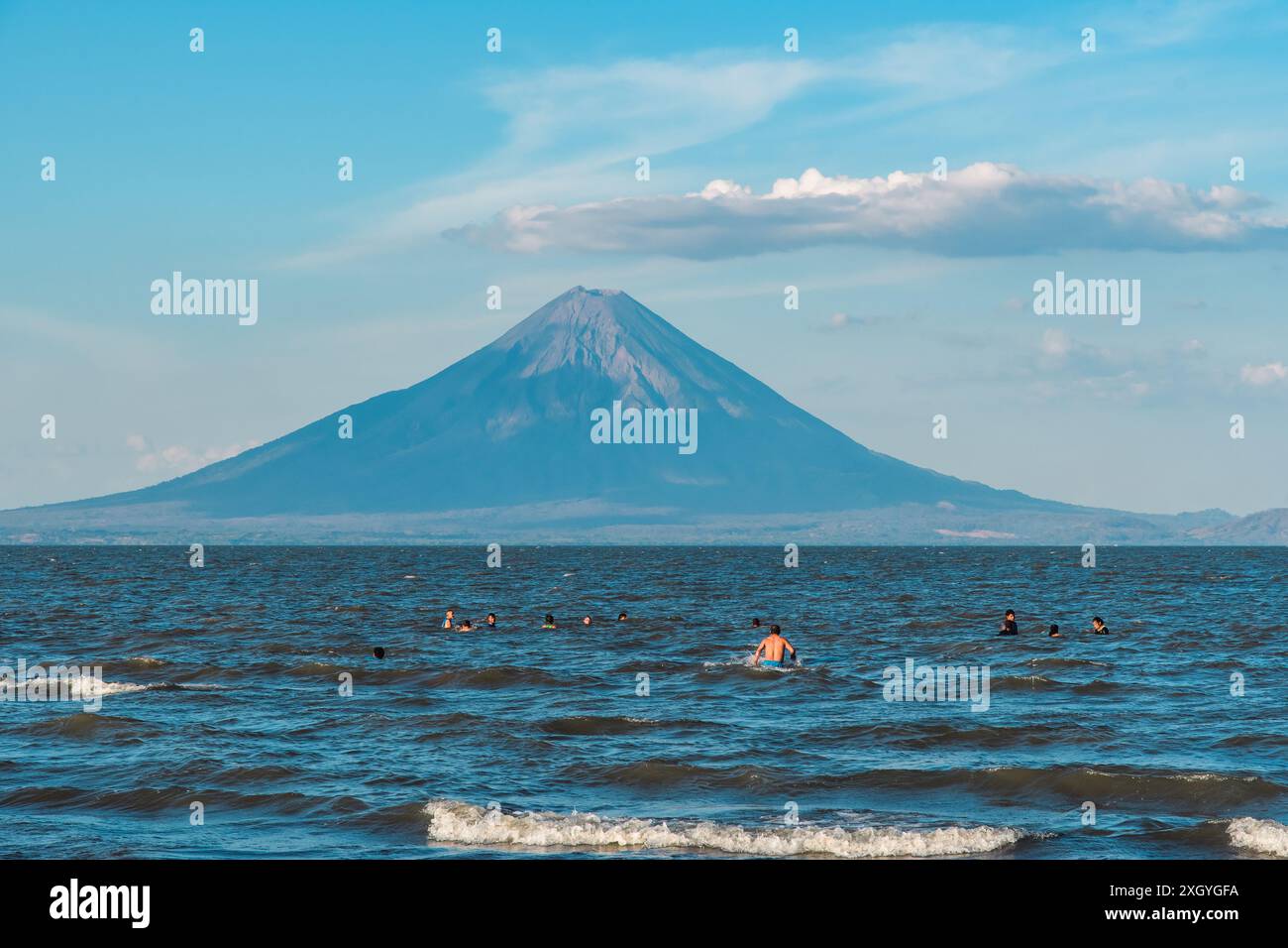 San Jorge, Nicaragua - 25. März 2019: Badende sonnen sich im Wasser des Nicaraguasees, während der Vulkan Concepción in Sicht ist. Stockfoto