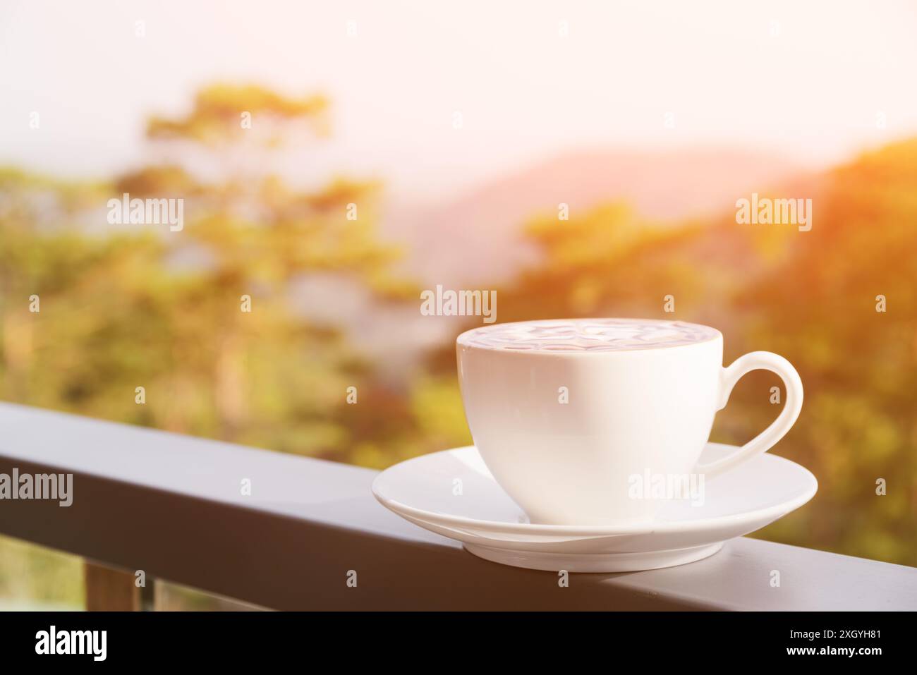 Tasse heißer Cappuccino-Kaffee auf Naturhintergrund. Frisches belebendes Getränk auf der Terrasse des Cafés. Getöntes Bild. Stockfoto
