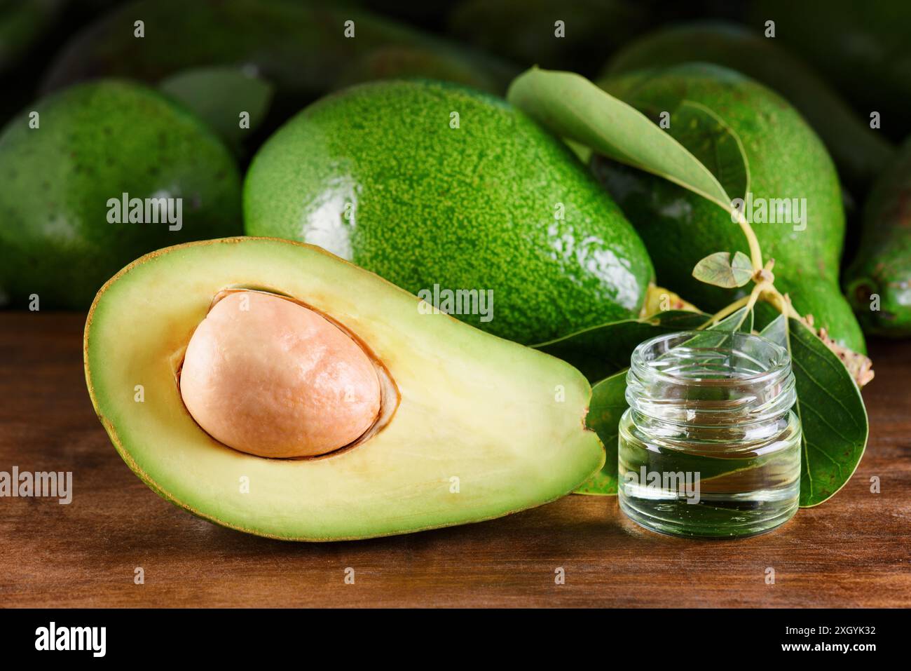 Reife grüne Avocados und frisches natürliches Avocadoöl auf Holztisch. Gesundes Öko-Produkt des ökologischen Landbaus. Haut-, Körper- und Haarpflege. Handgemachte Kosmetik Stockfoto