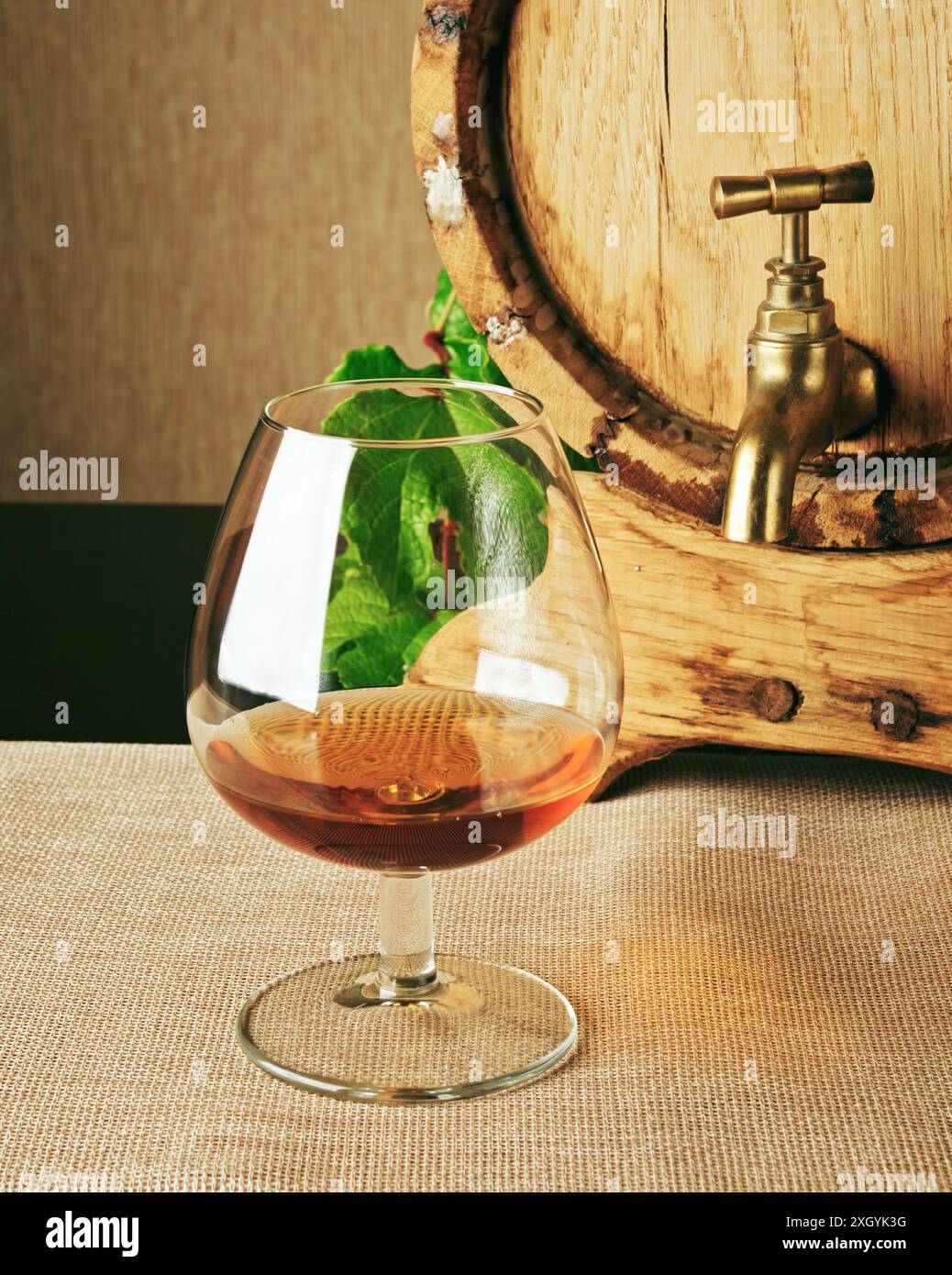 Ein Glas Brandy auf dem Tisch. Cognaczylinder ist rechts sichtbar. Weinerzeugnis. Klassisches alkoholisches Getränk. Stockfoto