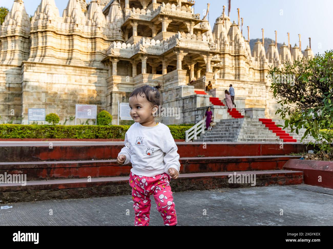 Niedliches Kind mit alter einzigartiger Tempelarchitektur mit hellblauem Himmel Hintergrund am Tag wird am ranakpur jain Tempel rajasthan indien aufgenommen. Stockfoto