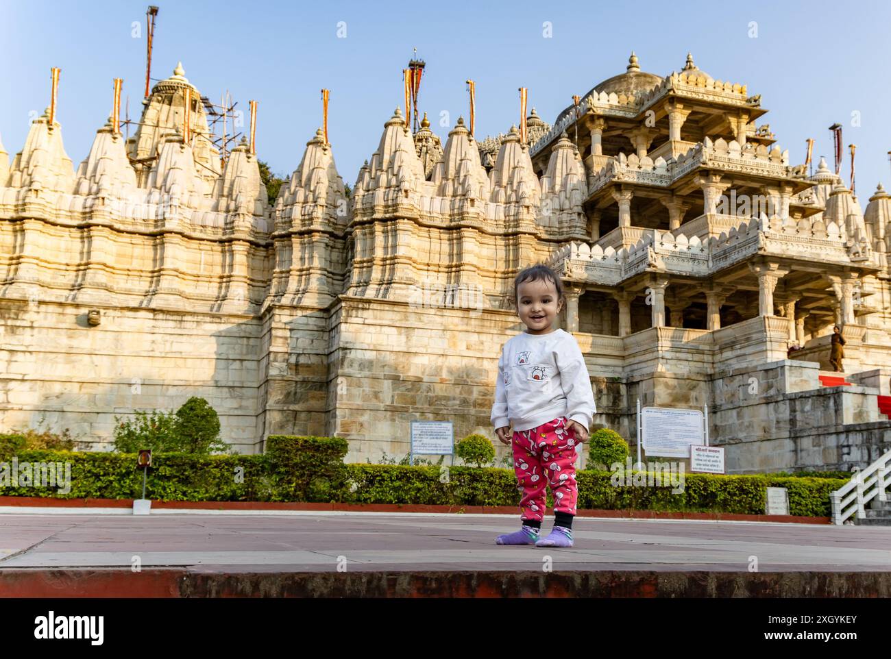Niedliches Kind mit alter einzigartiger Tempelarchitektur mit hellblauem Himmel Hintergrund am Tag wird am ranakpur jain Tempel rajasthan indien aufgenommen. Stockfoto