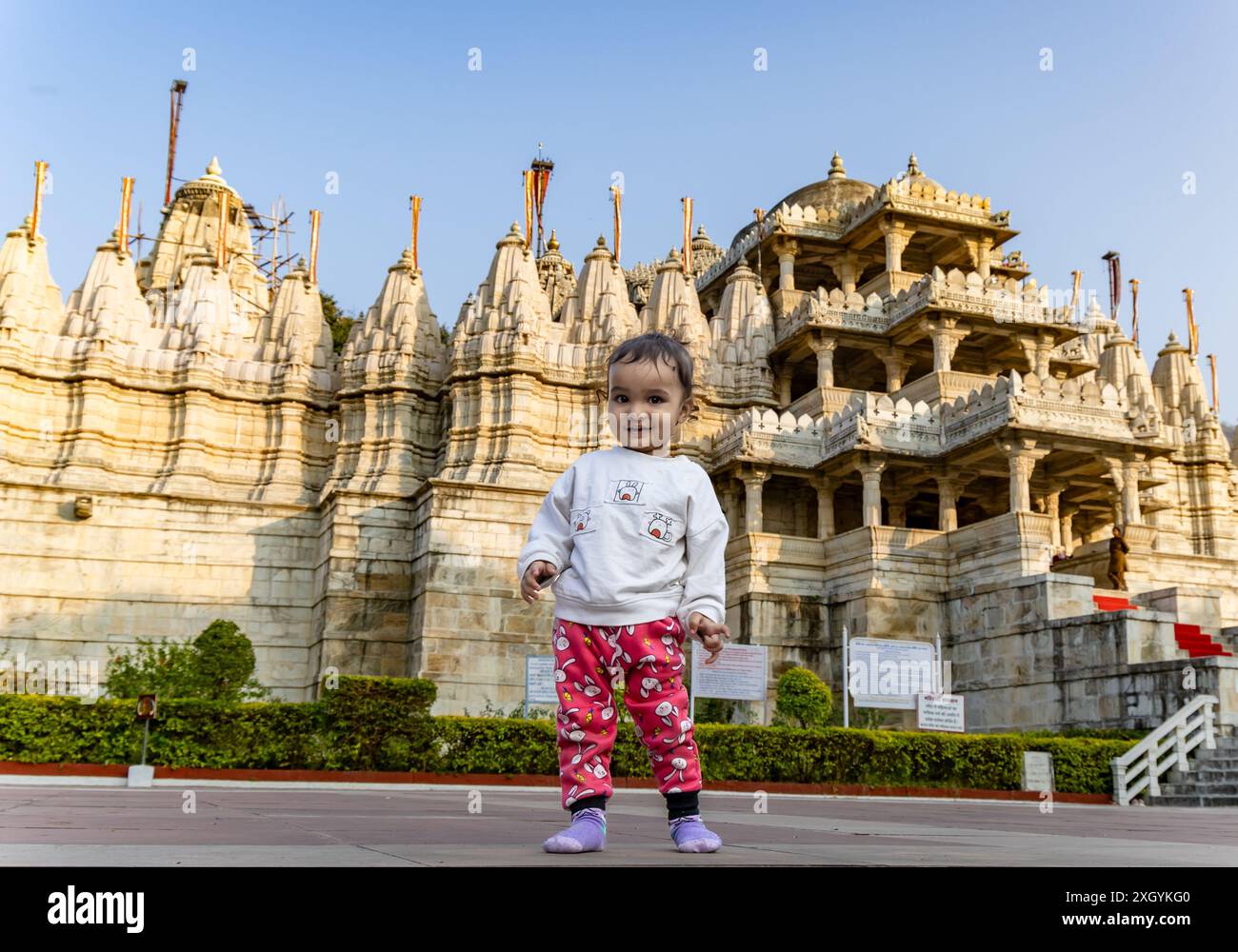 Niedliches Kind mit alter einzigartiger Tempelarchitektur mit hellblauem Himmel Hintergrund am Tag wird am ranakpur jain Tempel rajasthan indien aufgenommen. Stockfoto