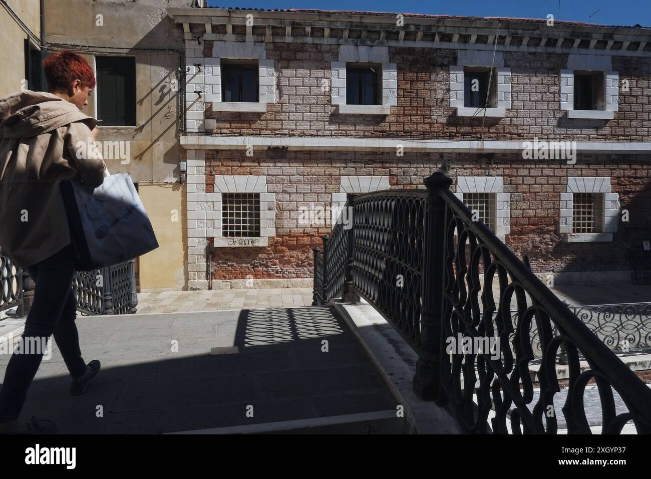 Venedig Italien, zweistöckige Gebäudefassade, gemauerte rustikale Ziegelsteine und Fensterumrandungen und Ponte de San Severo mit dekorativer Eisenbalustrade Stockfoto