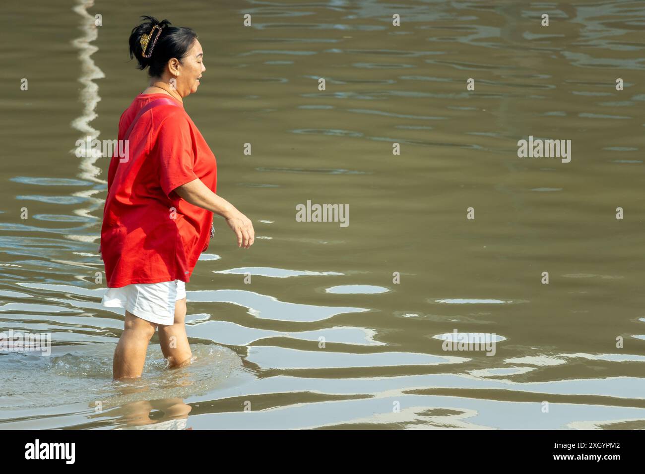 SAMUT PRAKAN, THAILAND, Februar 2024, Eine Frau waten durch eine überflutete Straße Stockfoto