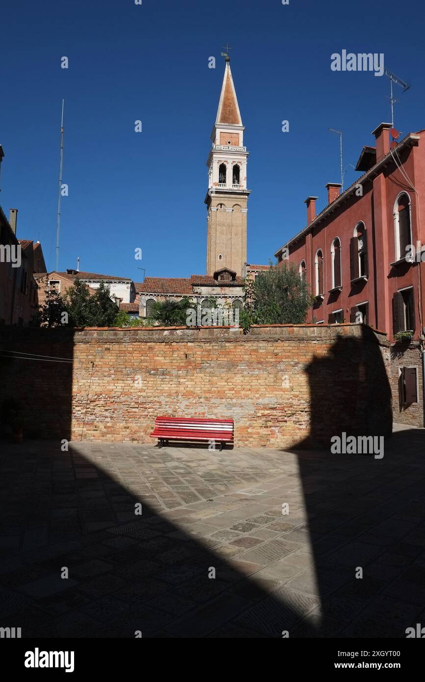 Verirren Sie sich in Venedig mit einer besonderen Aussicht, auf Ramo Seconda de la Vida eine rote Bank und der Glockenturm der Chiesa di San Francesco della Vigna im Sonnenlicht Stockfoto