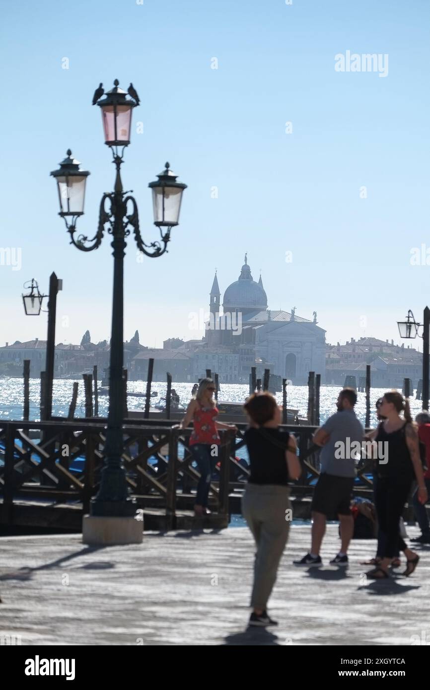 Eine Frau, die von einem Steg auf der Riva degli Schiavoni fotografiert wird, eine venezianische Lampe, Chiesa del Santissimo Redentore auf Giudecca gegenüber dem Bacon Stockfoto