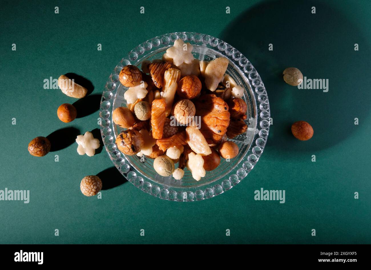 Reiscracker im japanischen Stil in einer Glasschale auf grünem Hintergrund Stockfoto