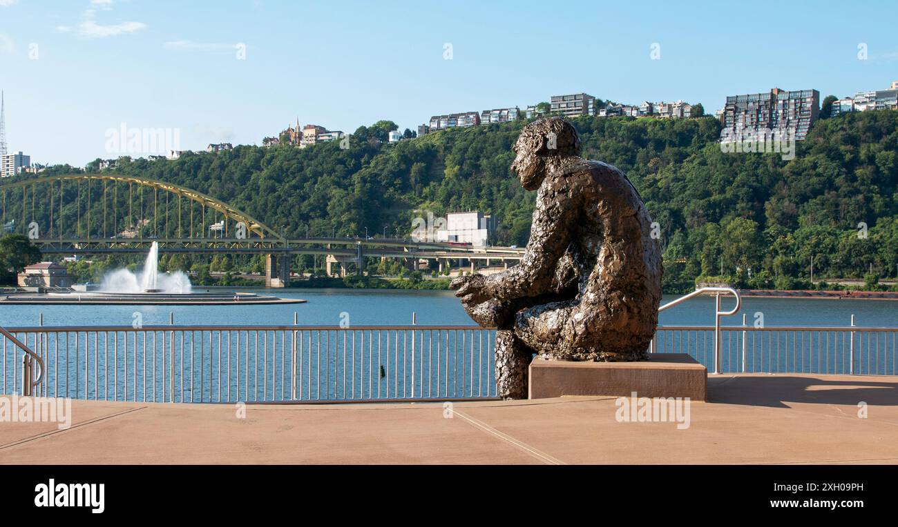 Pittsburgh, Pennsylvania, USA - 8. August 2023: Die Thinking man Statue von Mister Fred Rogers bewundert die Wasserfontäne des Point State Park. Stockfoto