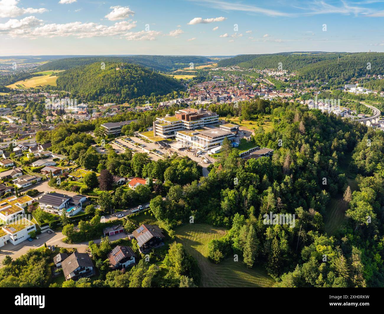 Luftaufnahme einer Stadt in grüner Umgebung, viele Häuser und ein großes Gebäude auf einem Hügel, blauer Himmel im Sommer, Krankenhaus, Nagold, Schwarzwald, Deutschland Stockfoto