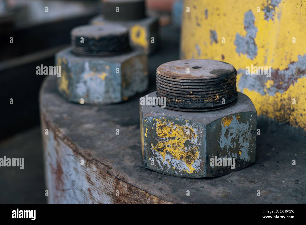 Große rostige Schrauben mit abblätternder gelber Farbe, Verschleiß in industrieller Umgebung, Nahaufnahme. Stockfoto