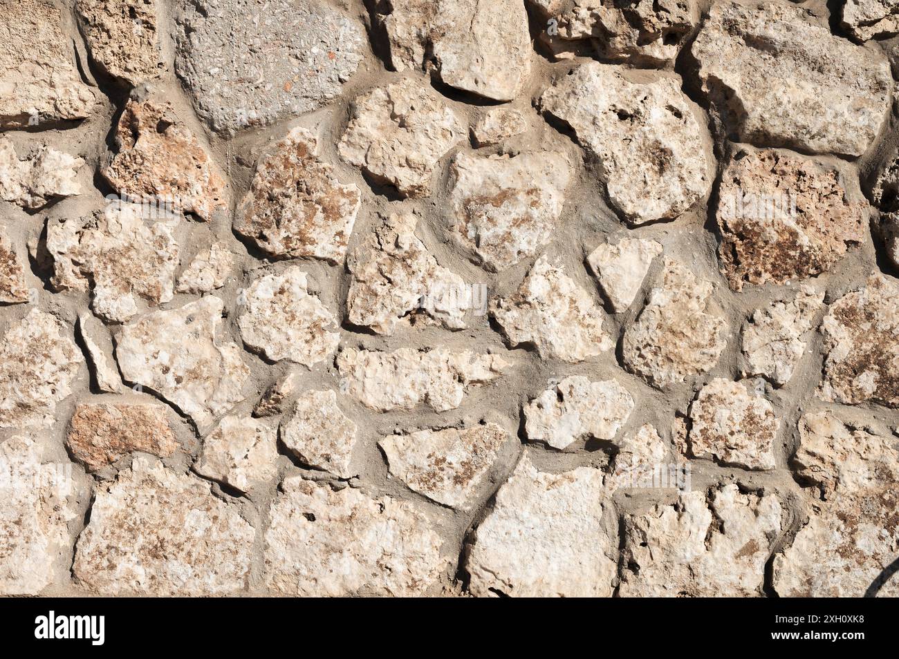 Die Steinwand ist mit Naturstein ausgekleidet und zementiert. Natürliches Baumaterial. Mittelalterlicher Hintergrund Stockfoto