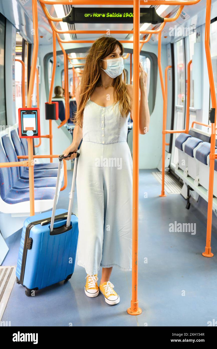 Frau mit Gesichtsmaske, die während des Covid-19-Ausbruchs mit der Straßenbahn unterwegs war. Hochwertige Fotos Stockfoto