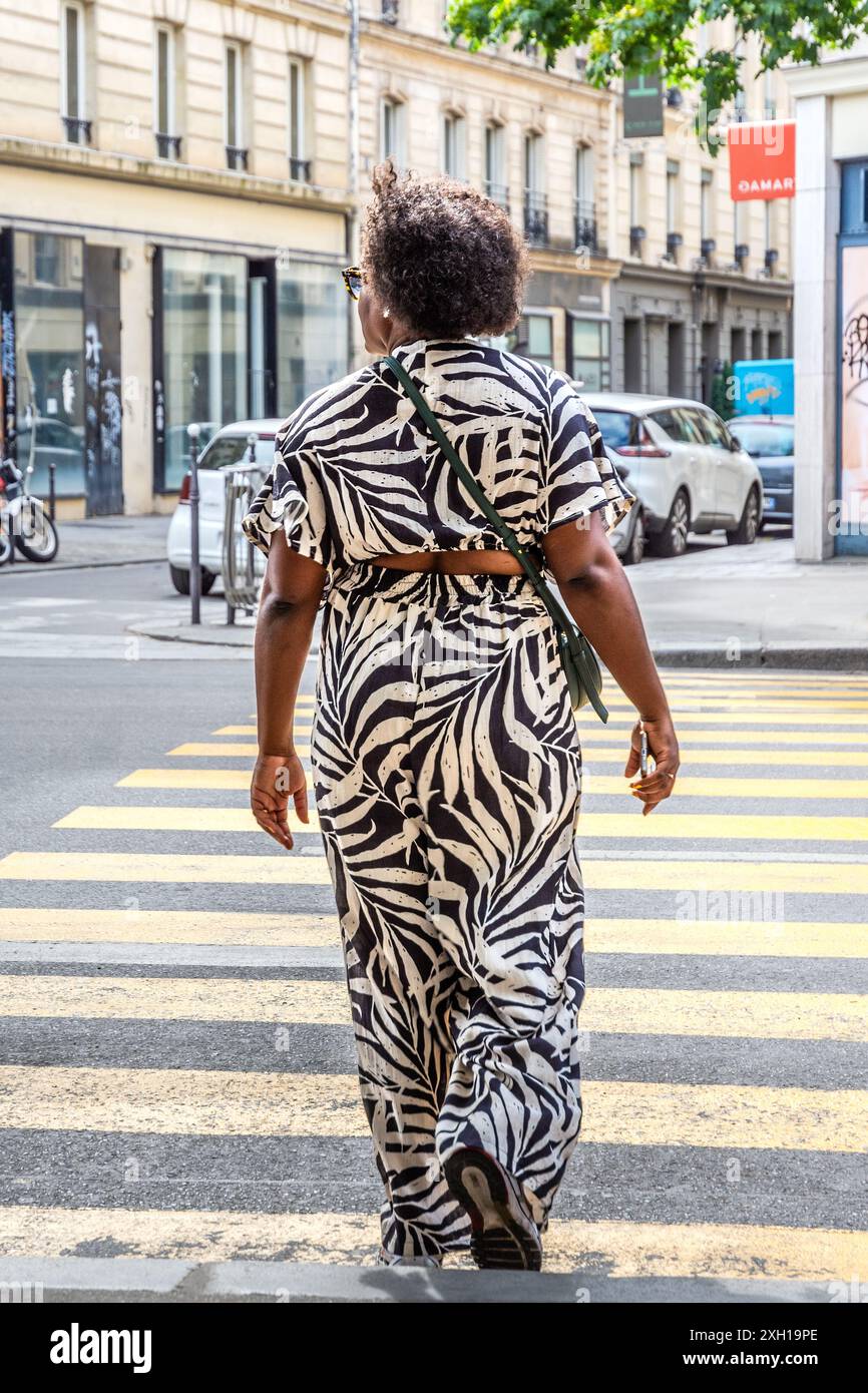 Afrikanische Frau im abstrakten schwarz-weißen Hosenanzug Kleid über die Straße - Paris 75004, Frankreich.Hose Stockfoto