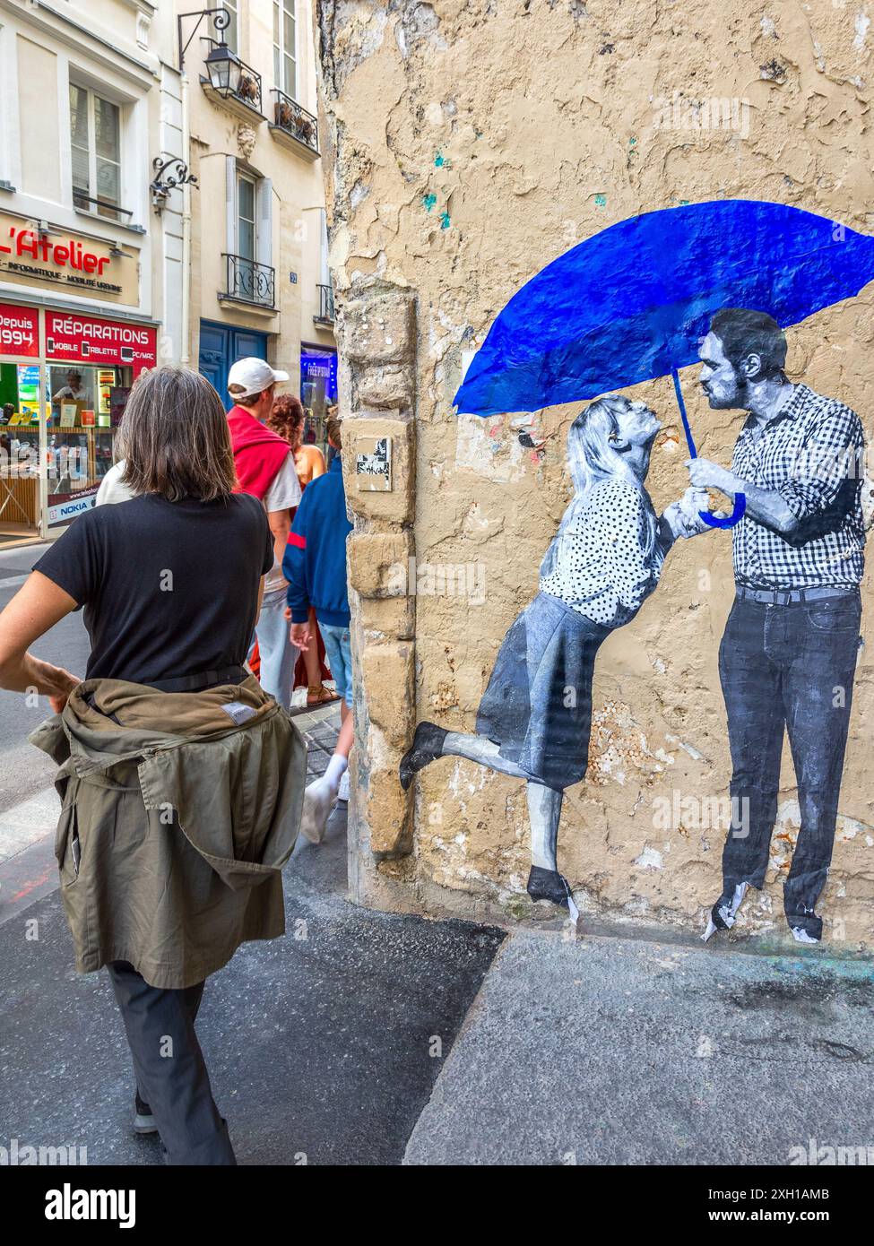 Fotomontage eines Paares unter blauem Schirm an der Rue de la Verrerie, Paris 75004, Frankreich. Stockfoto