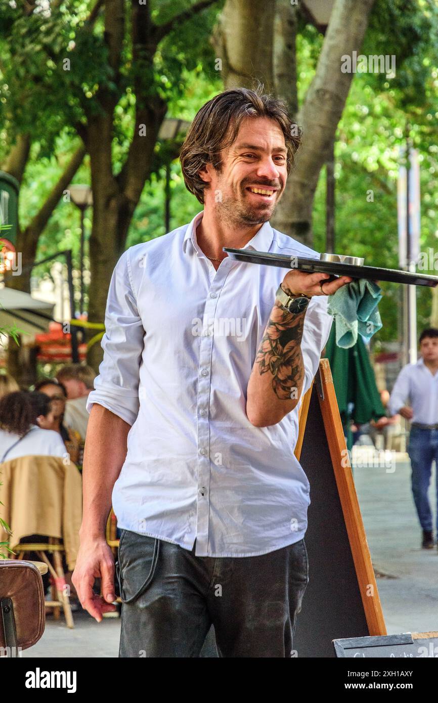 Kellner im 'Little Cafe' mit einem Tablett während einer Pause - Paris 75004, Frankreich. Stockfoto