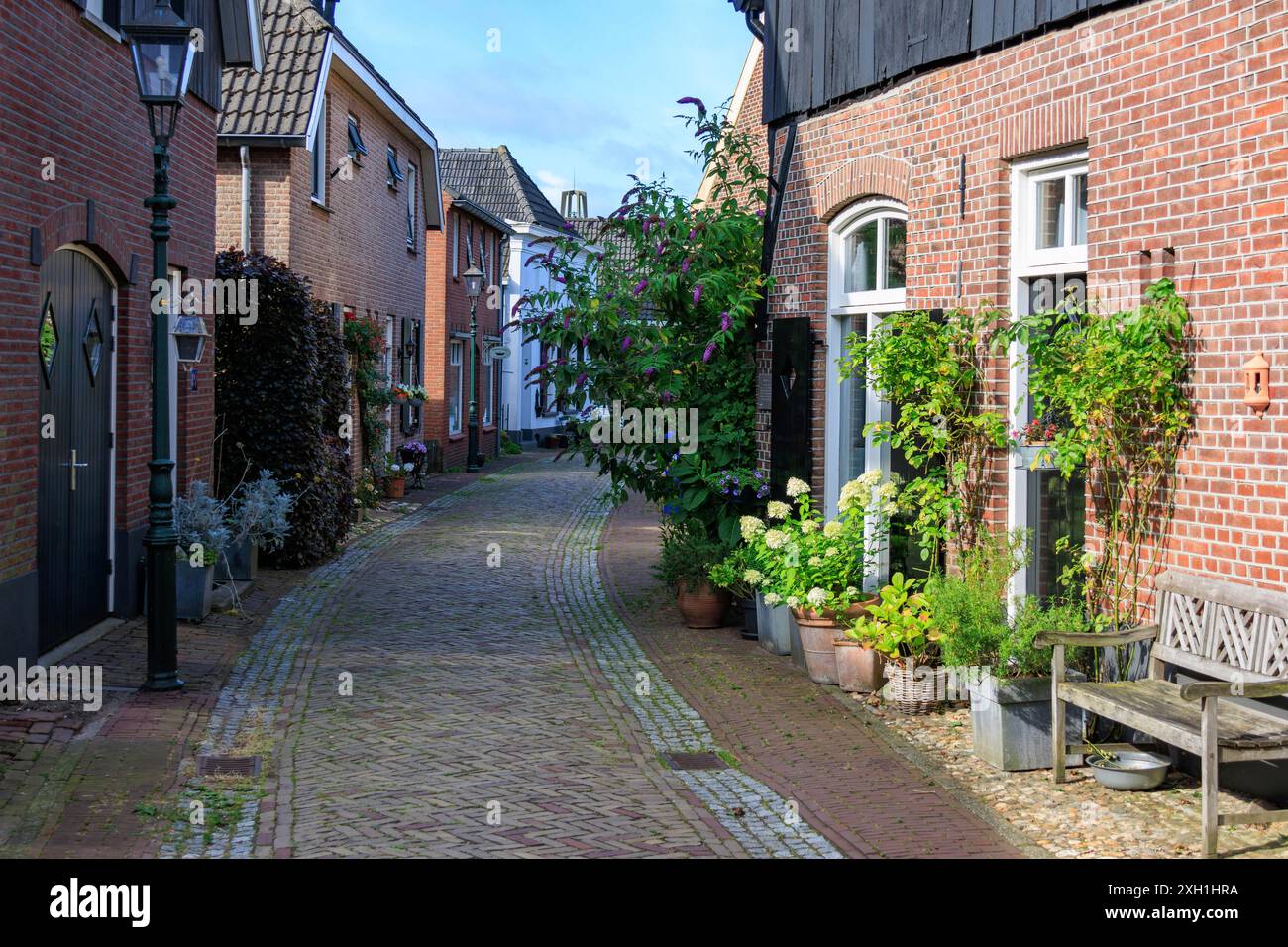 Gepflasterte Gasse mit historischen Backsteinmauern, Fenstern und Topfpflanzen. Eine ruhige und malerische Atmosphäre, Bredevoort, gelderland, niederlande Stockfoto