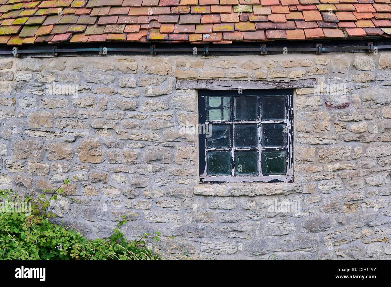 Altes Holzfenster in einem Backsteingebäude mit rotem Ziegeldach Stockfoto