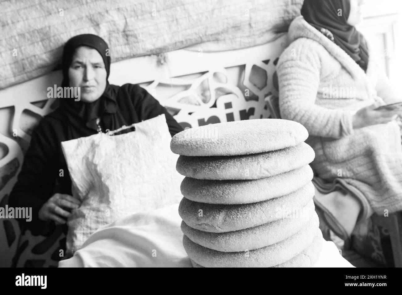 Schwarzweiß-Fotografien einiger Verkäufer von Khobz, typisch marokkanisches Brot, warten an der Tür eines Marktes mit ihren Broten in Türmen. Stockfoto