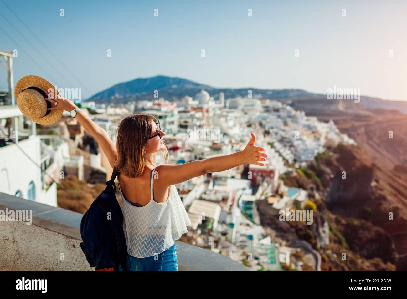 Die Touristenfrau erhob die Arme und blickt auf die traditionelle Architekturlandschaft von Fira, Insel Santorin. Ausflug im Sommerurlaub Stockfoto Die Touristenfrau erhob die Arme und blickt auf die traditionelle Architekturlandschaft von Fira, Insel Santorin. Ausflug im Sommerurlaub Stockfoto