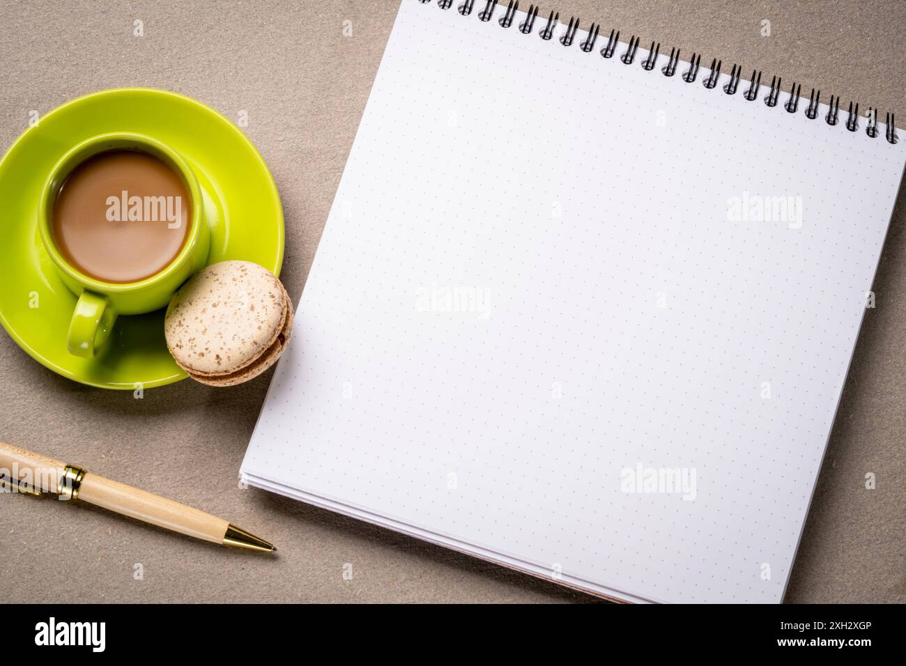 Leeres Spiralnotizbuch mit gepunktetem Papier, flach aufgelegt mit Kaffee auf strukturiertem Kunstdruckpapier Stockfoto