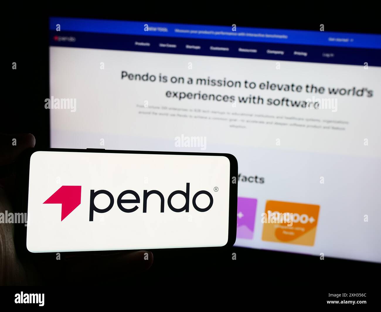 Person, die ein Mobiltelefon mit dem Logo des US-Softwareunternehmens Pendo.io Inc. Vor der Webseite des Unternehmens hält. Schwerpunkt auf dem Display des Telefons. Stockfoto