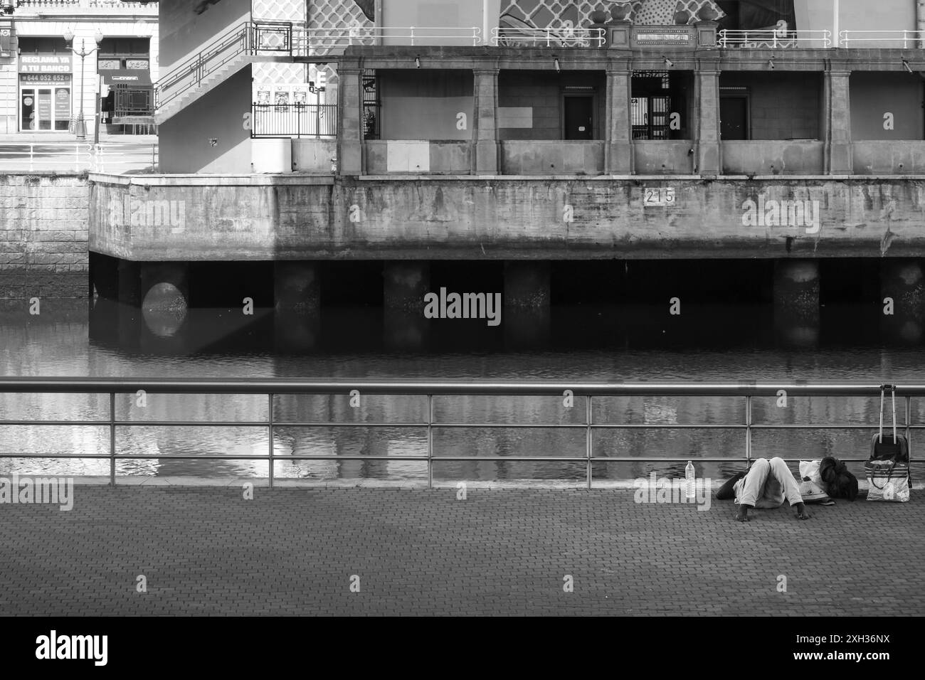 Bilbao, Baskenland, Spanien, 13. August 2023: Obdachloser schläft auf der Straße neben dem Fluss Nervion in Bilbao, Spanien Stockfoto