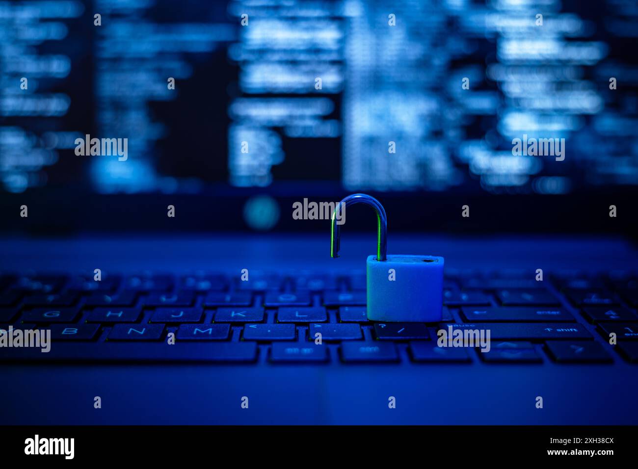 Auf der Tastatur eines Laptops befindet sich ein blaues Vorhängeschloss mit einem unscharfen Code-Hintergrund. Stockfoto
