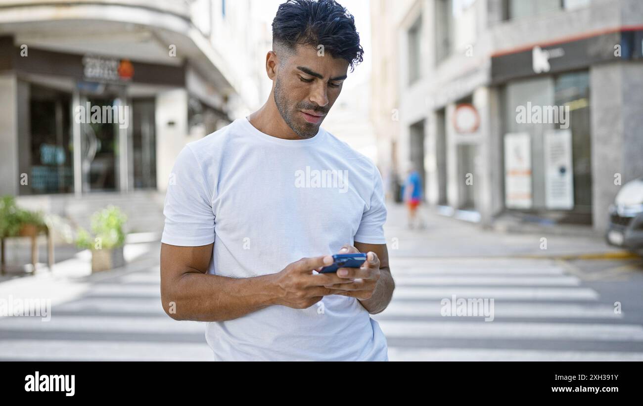Hübscher hispanischer Mann mit Smartphone in einer geschäftigen städtischen Straßenszene Stockfoto