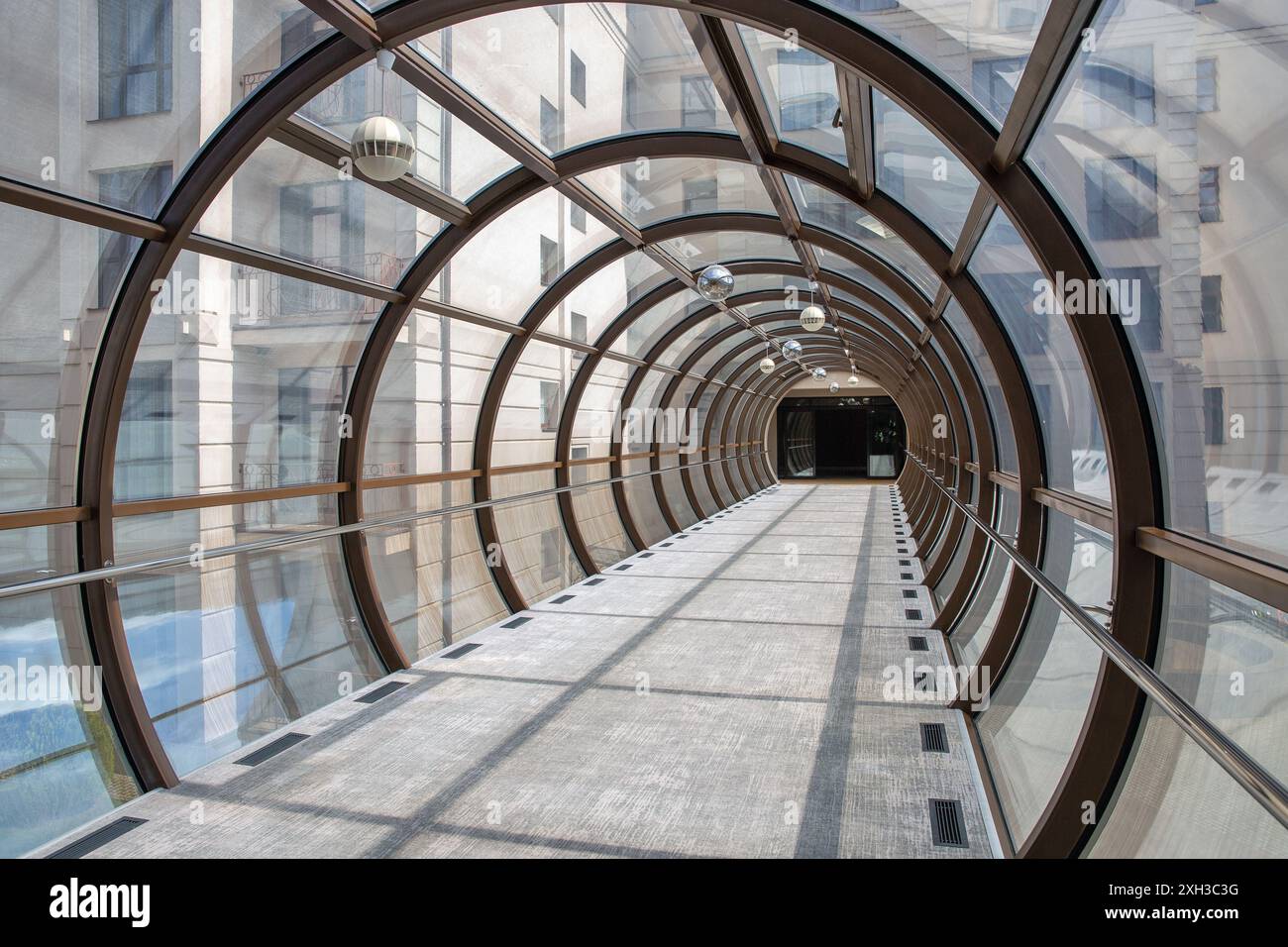 Fußbrücke gerader Tunnel aus Pfählen und Glas zwischen Gebäuden mit abstraktem Design im Inneren. Stockfoto