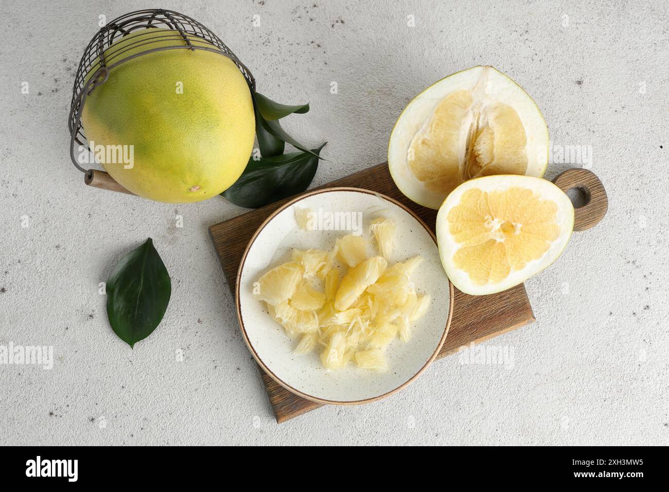 Teller und Korb mit frischen Pomelo-Früchten auf weißem Hintergrund Stockfoto