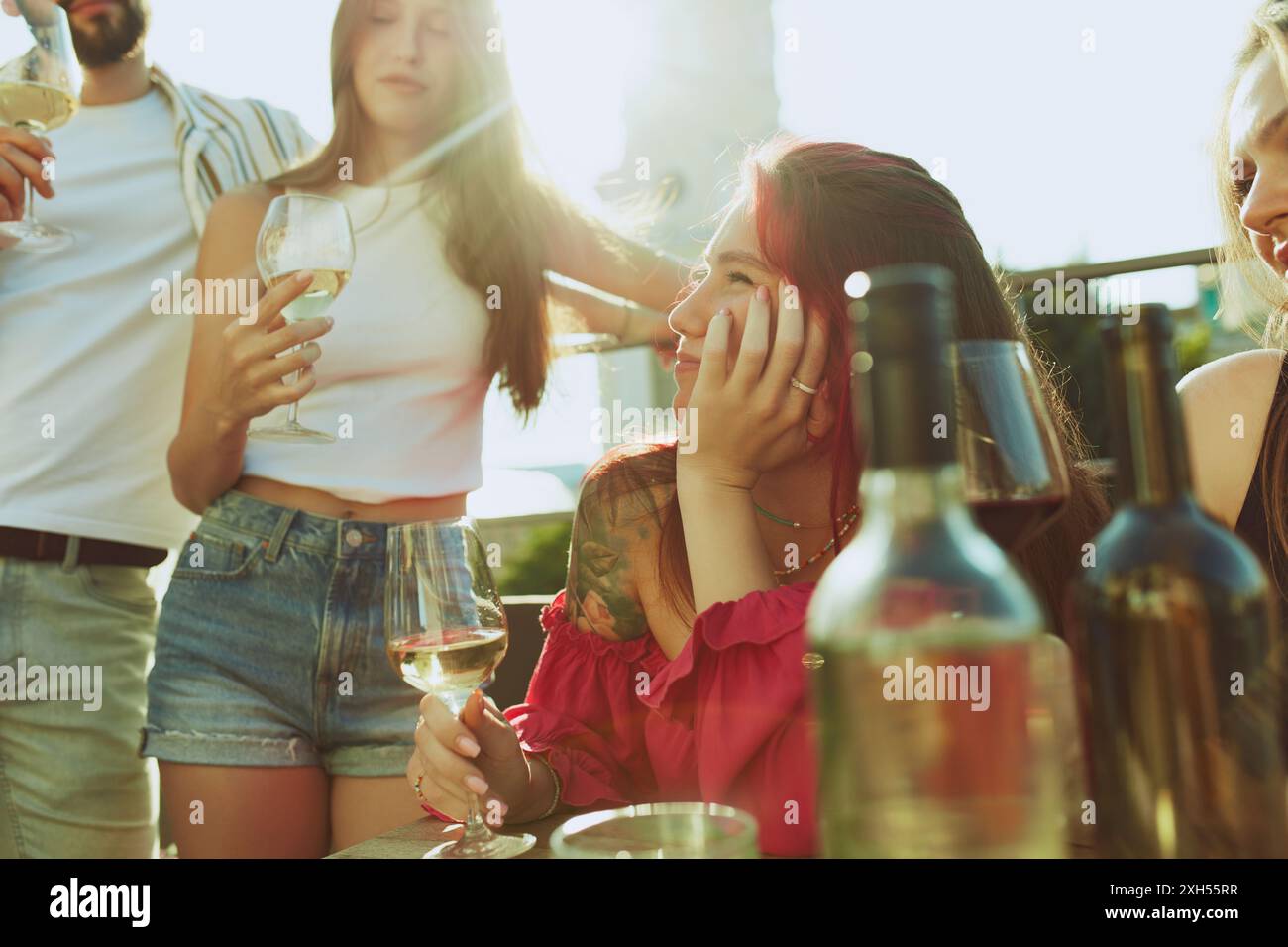 Eine Gruppe junger Erwachsener hebt ihre Gläser in Toast, ihr Lächeln spiegelt die Freude an einem heißen Sommertag wider. Party im Freien. Stockfoto