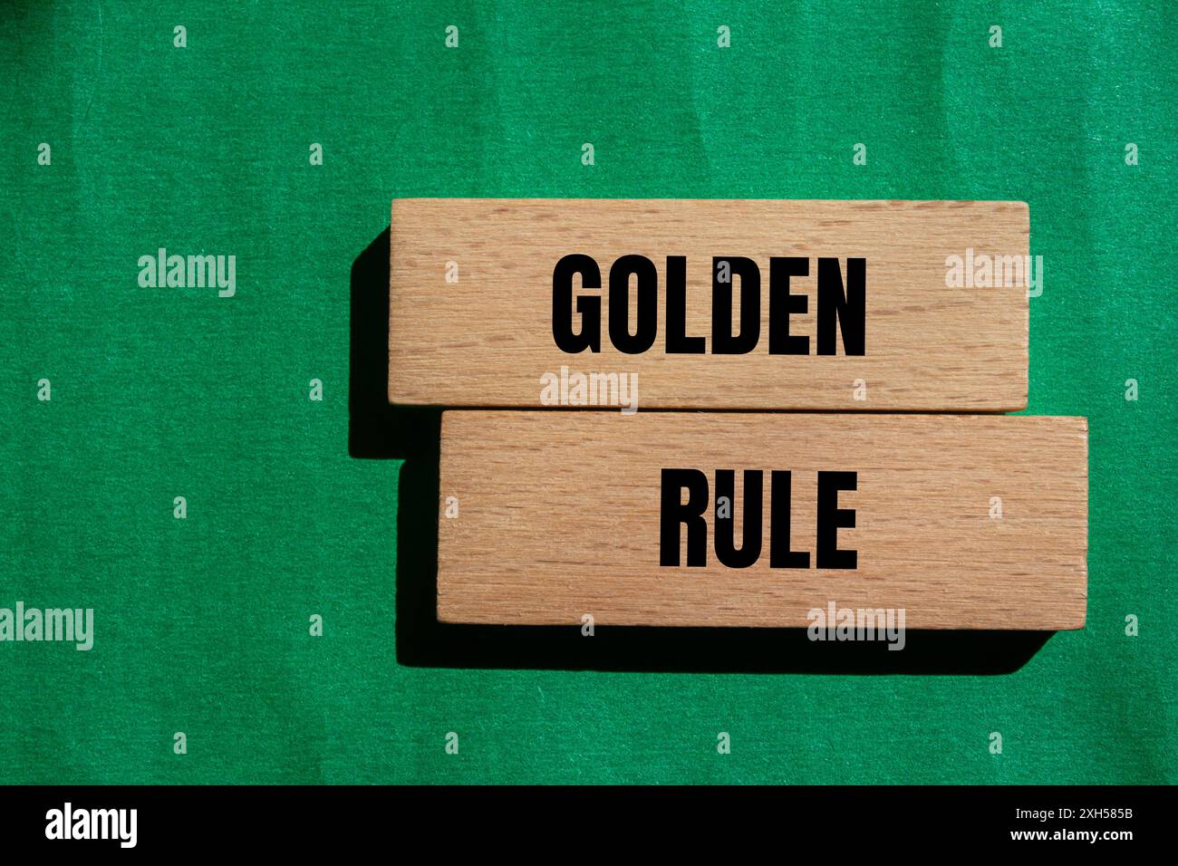 Goldene Regel-Nachricht auf Holzblöcken mit grünem Hintergrund. Konzeptionelles goldenes Regelsymbol. Kopierbereich. Stockfoto