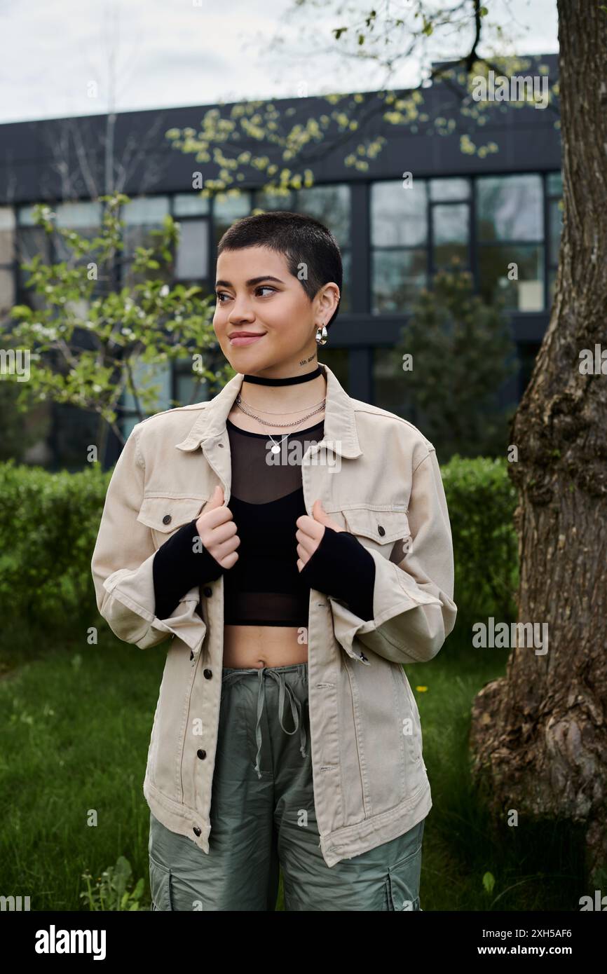 Eine junge Frau steht anmutig vor einem hoch aufragenden Baum und verbindet sich mit der Natur. Stockfoto