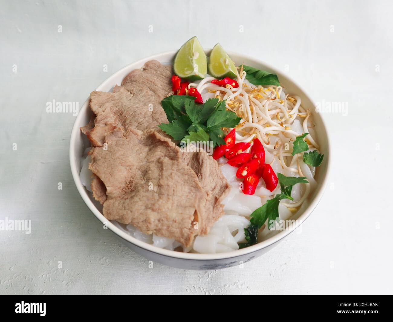 Eine Schüssel Pho Bo traditionelle Suppe mit Rindfleisch, Reisnudeln, Ingwer, Limette, Chili in einer Schüssel. Nahaufnahme. Vietnamesische Küche auf schwarzem Hintergrund Stockfoto