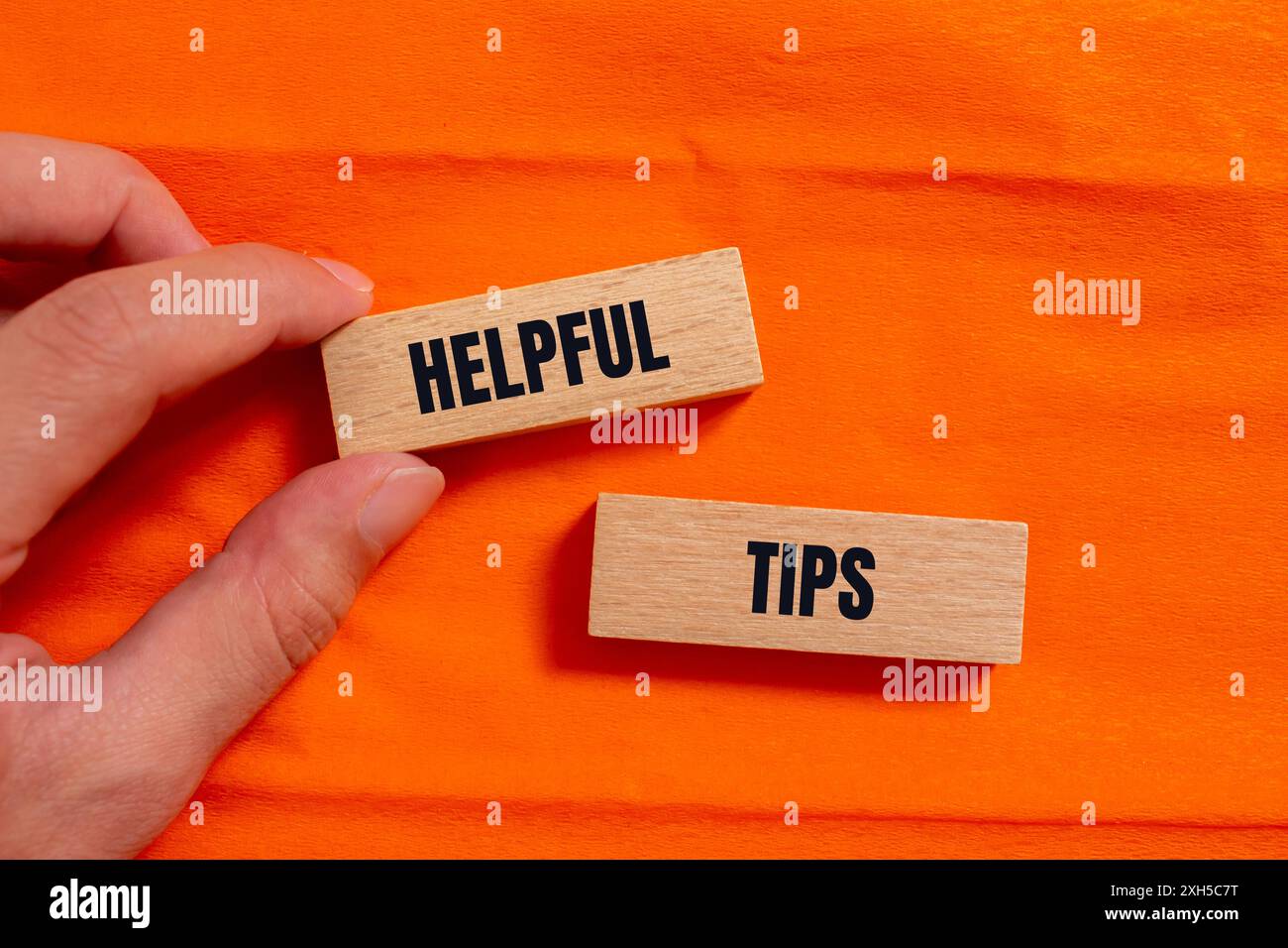 Hilfreiche Tipps auf Holzblöcken mit orangefarbenem Hintergrund. Symbol für hilfreiche Tipps. Kopierbereich. Stockfoto