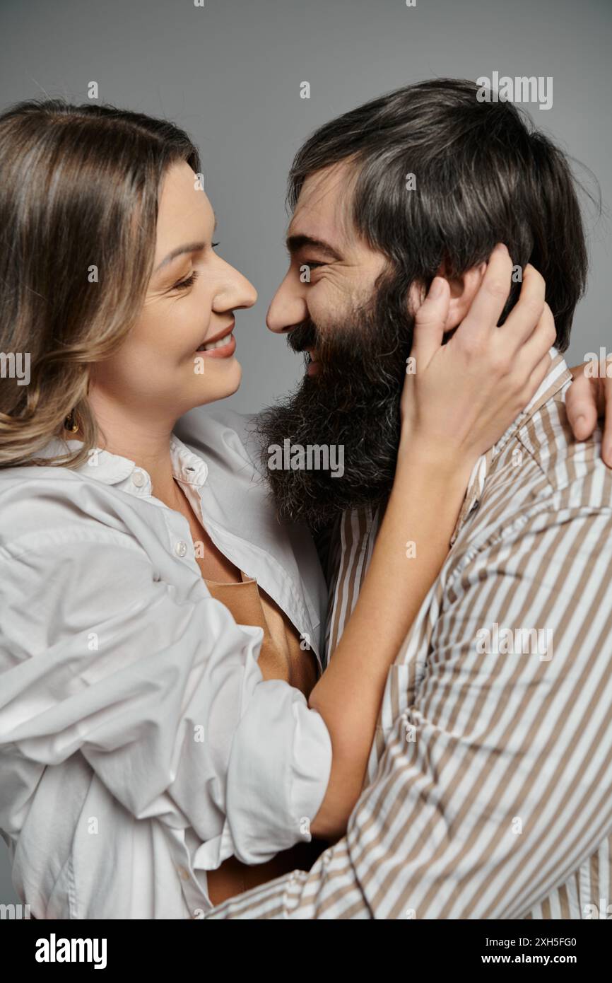 Ein liebevolles Paar in raffinierter Kleidung teilt einen zärtlichen Moment mit leidenschaftlichen Blicken. Stockfoto