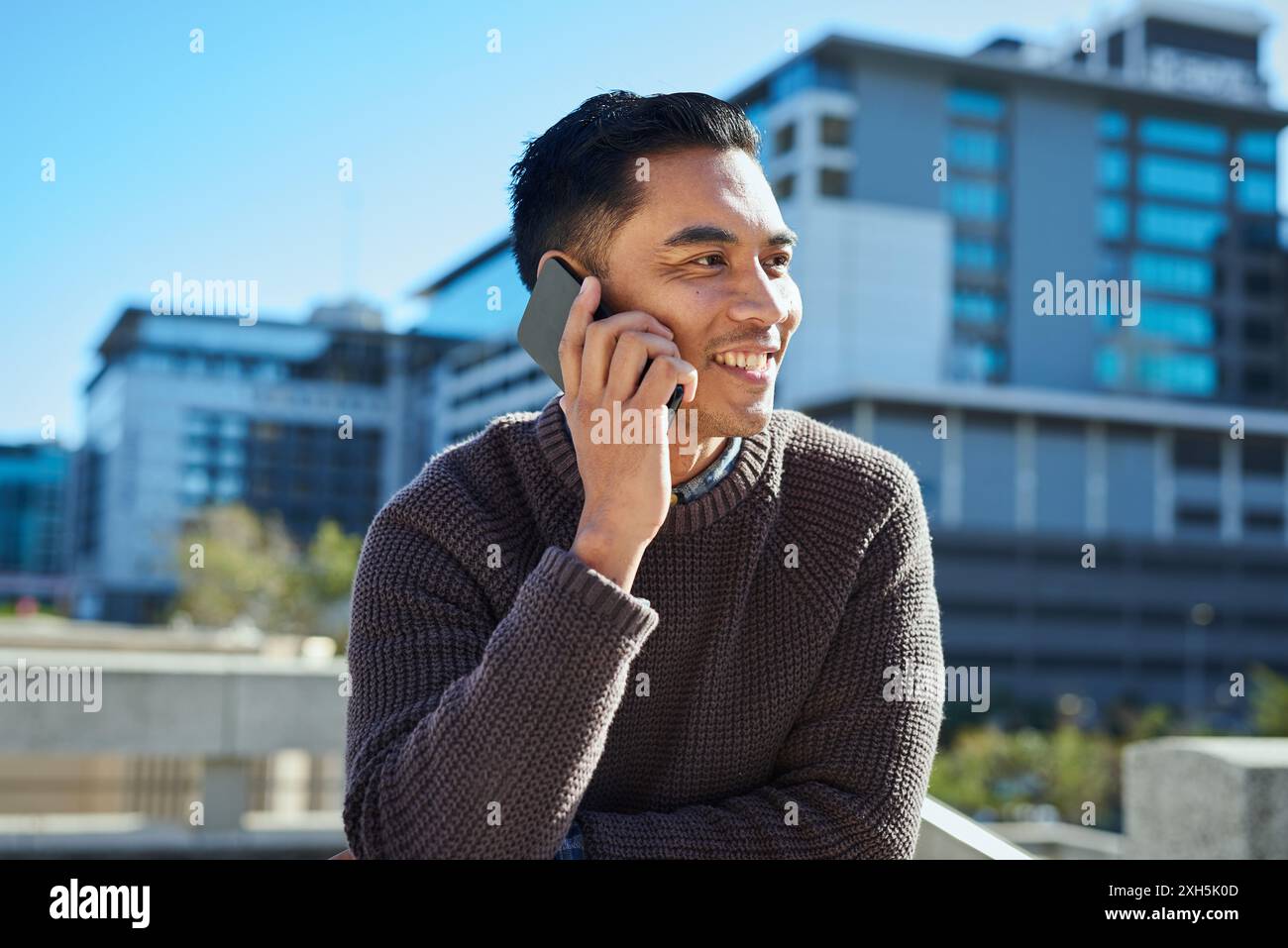 Lächelnder Urban Professional, der im Freien in der Stadt auf dem Handy spricht Stockfoto