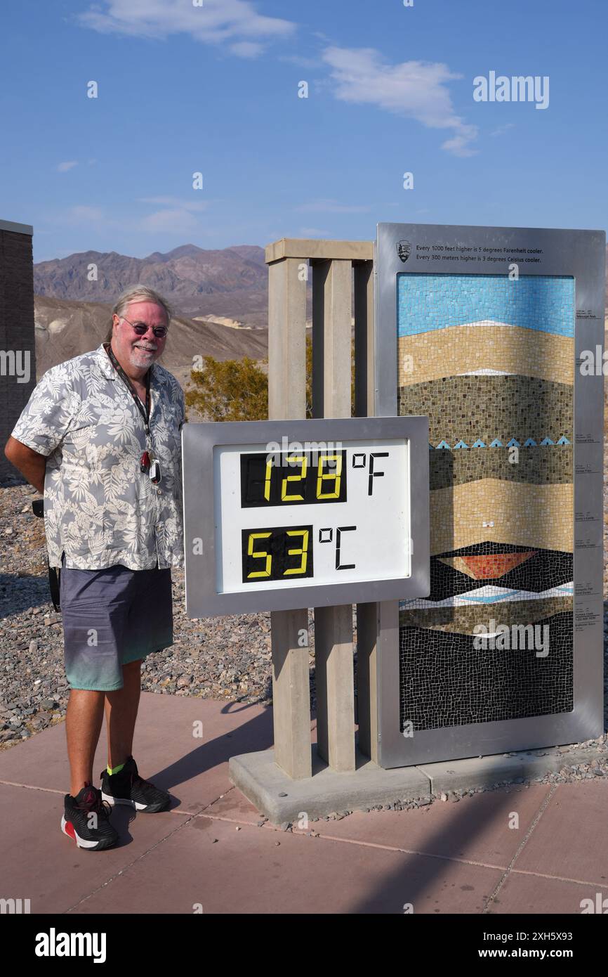 Jay Christensen von Sherman Oaks, Kalifornien, posiert mit dem Thermometer im Furnace Creek Visitor Center, das 128 Grad Fahrenheit (53 Grad Celsius) in de anzeigt Stockfoto