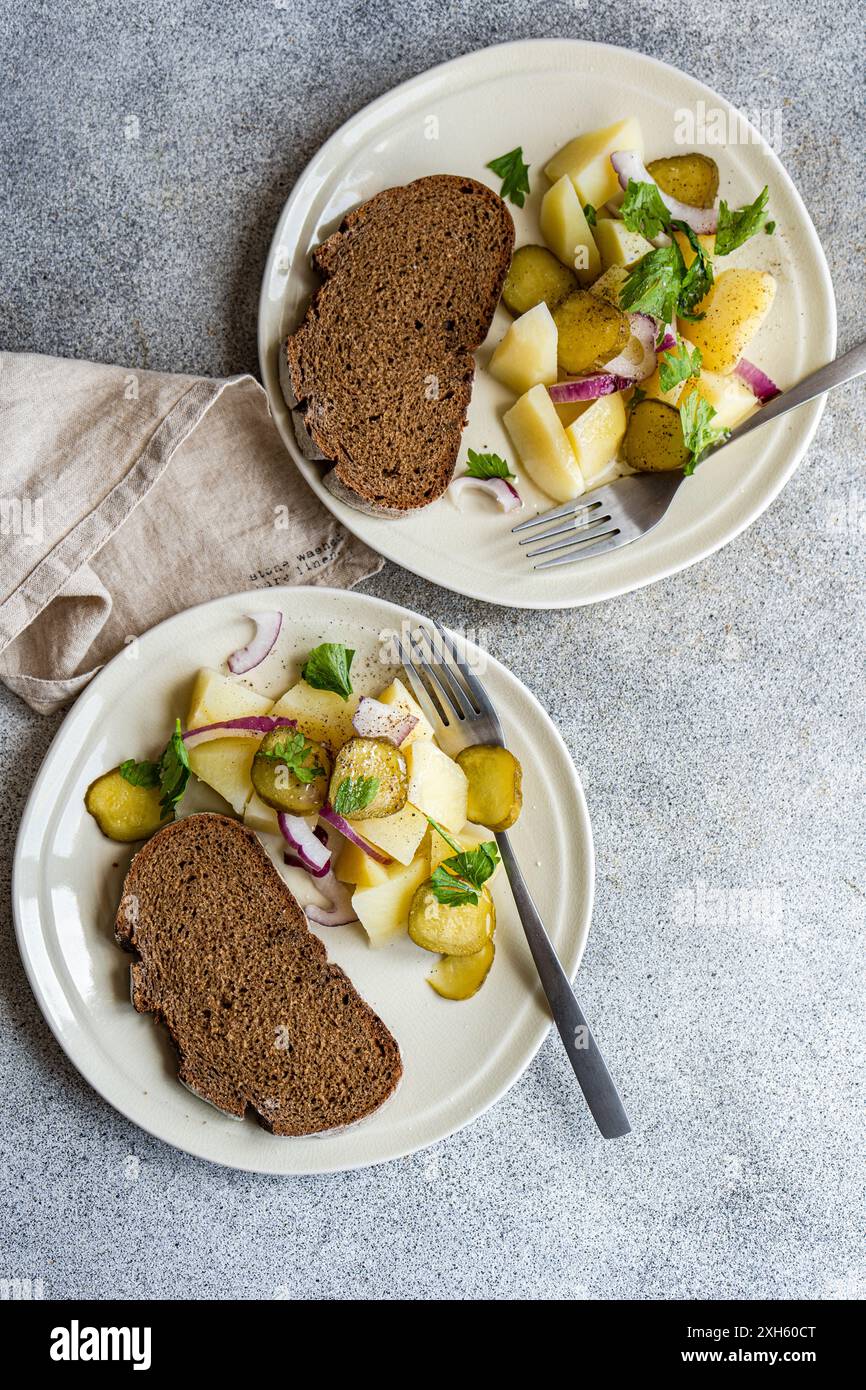 Kartoffelsalat mit roten Zwiebeln und fermentierten Cucmber auf dem Betontisch Stockfoto