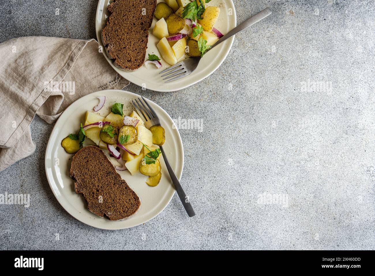 Kartoffelsalat mit roten Zwiebeln und fermentierten Cucmber auf dem Betontisch Stockfoto
