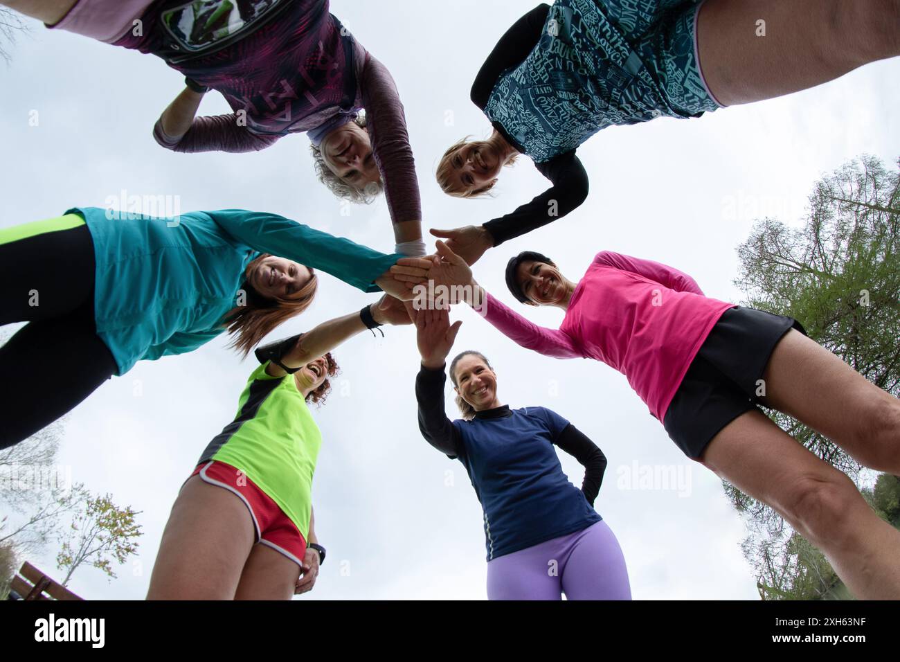 Eine Gruppe weiblicher Athleten schließt sich in einer Gruppe zusammen und zeigt ihren Teamgeist und ihre Motivation während eines Outdoor-Trainings Stockfoto