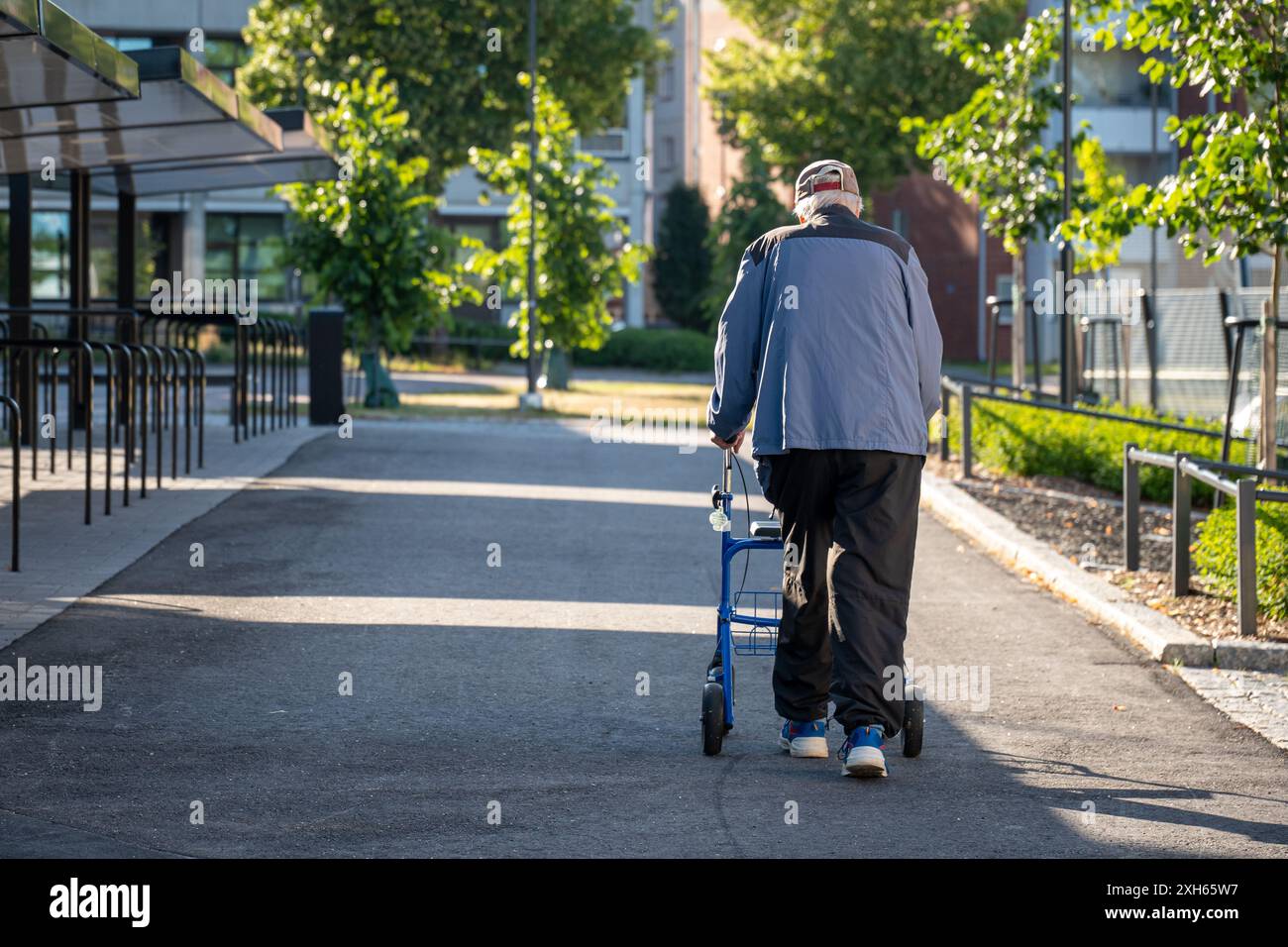 Älterer Mann, der allein draußen mit einem Rollator läuft Stockfoto