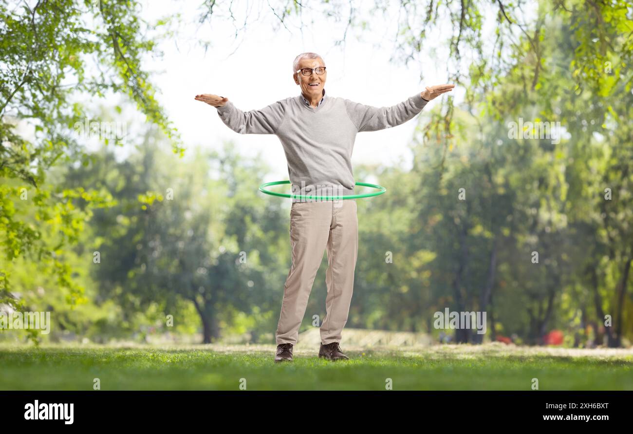 Ein älterer Herr spinnt einen Hula Hoop in einem Park Stockfoto