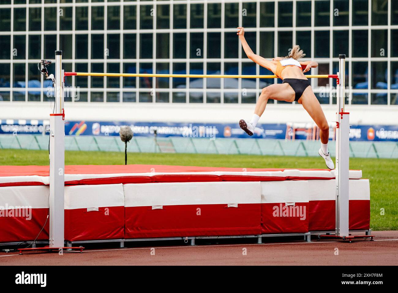 Weibliche Athletin hat beim Leichtathletikwettbewerb einen erfolgreichen Hochsprung versucht Stockfoto